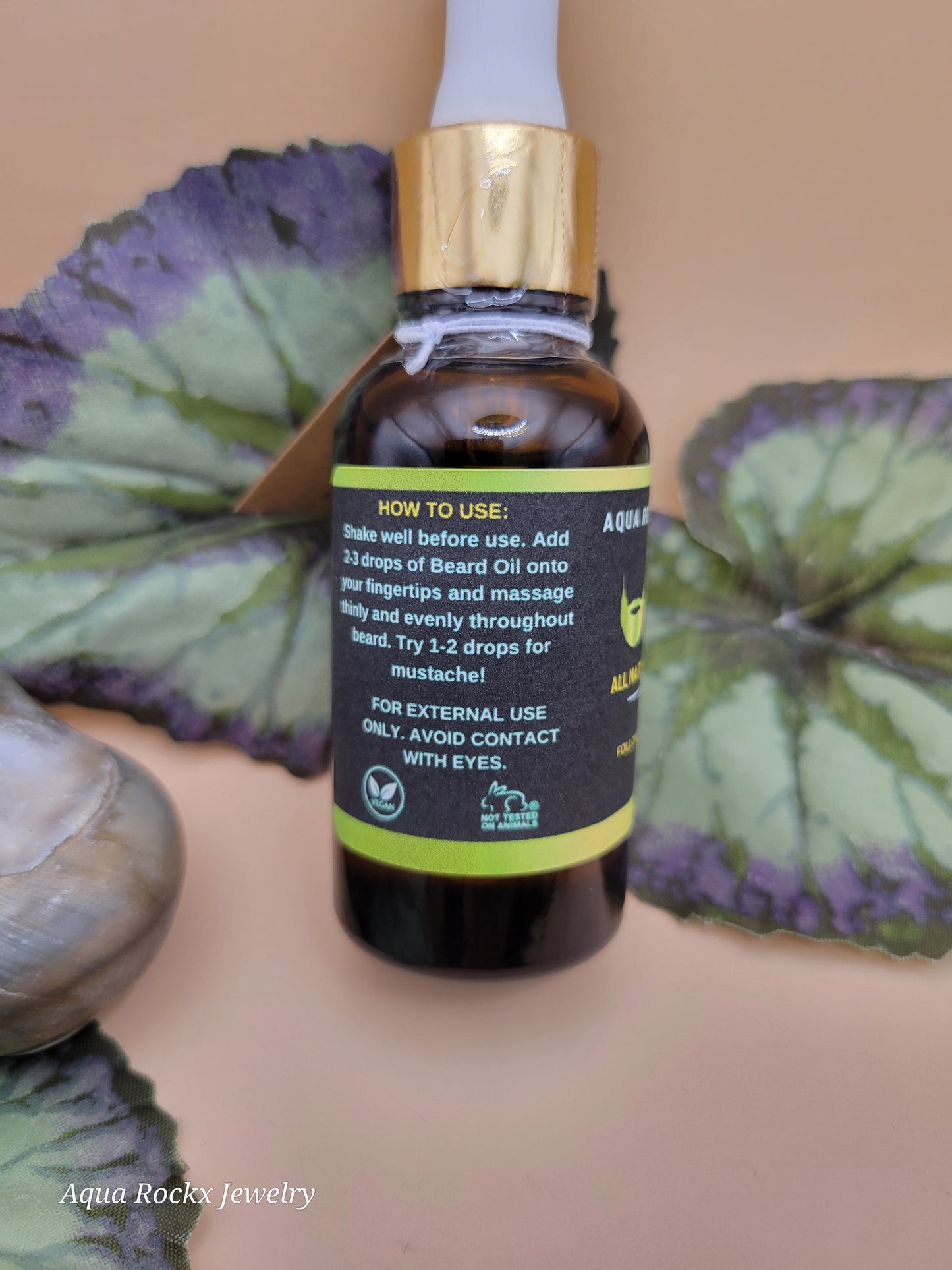 Bottle of essential oil with a dropper held over a leafy plant