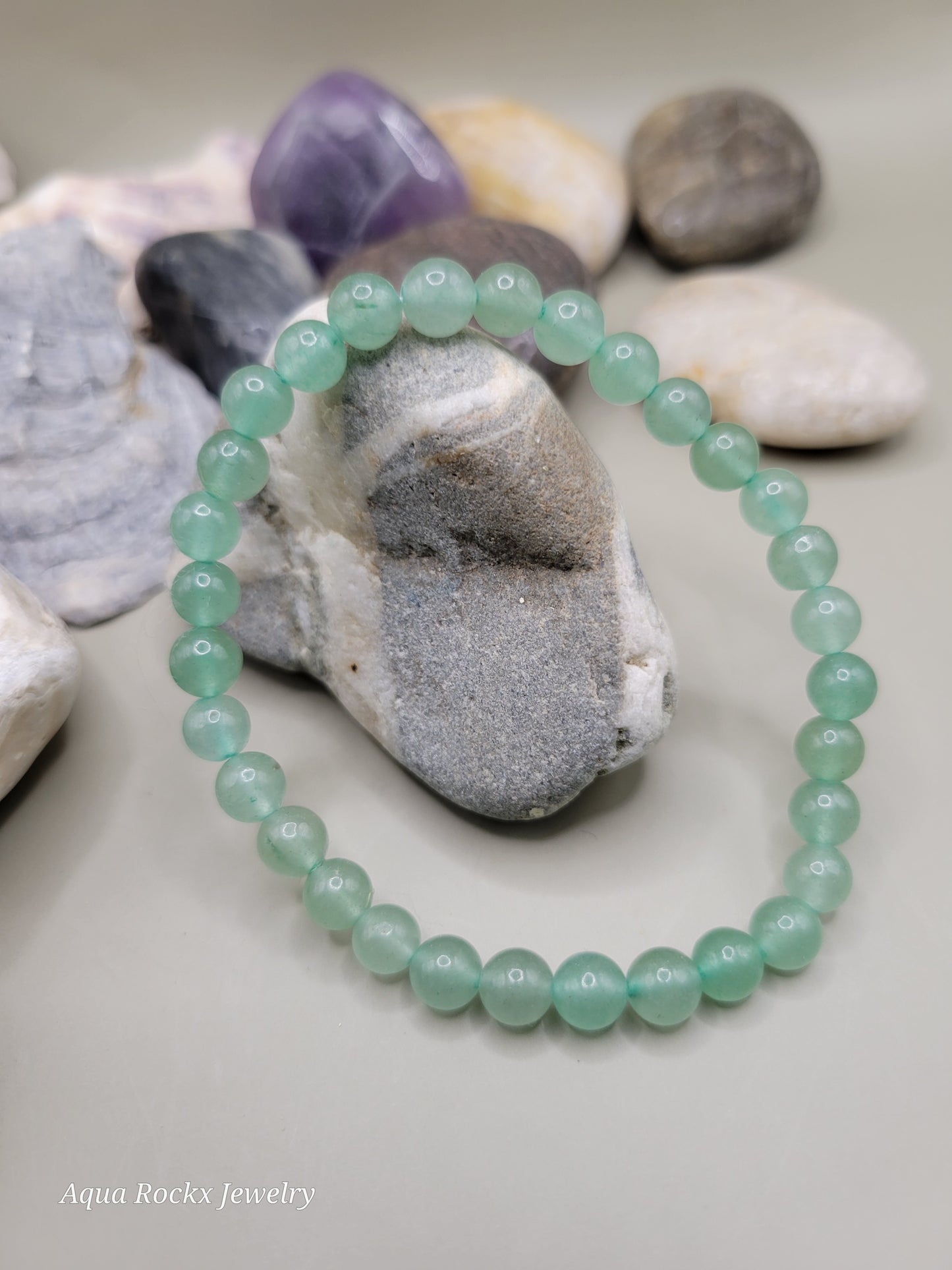 Green beaded bracelet on a stack of seashells.
