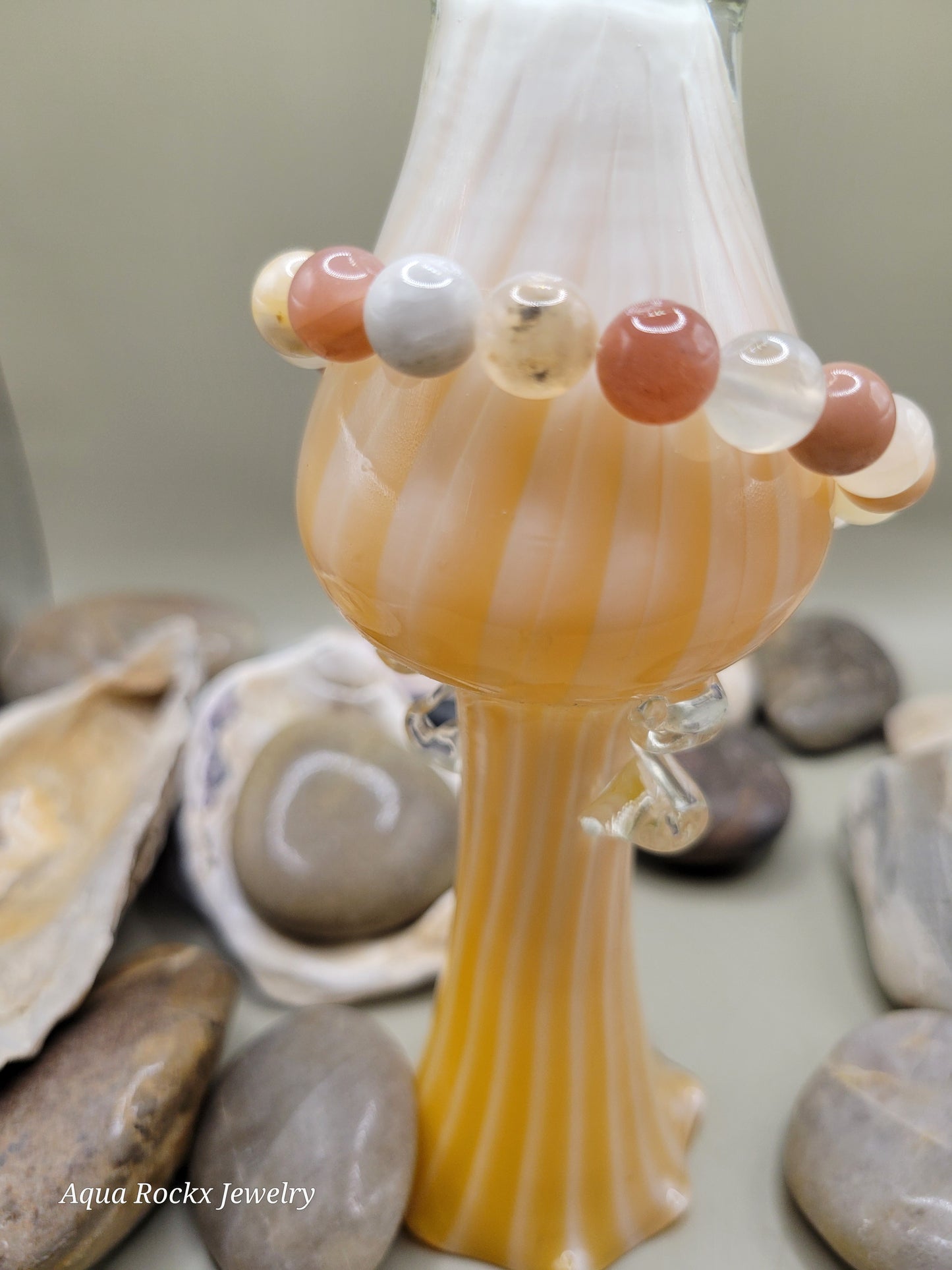 Multi color Moonstone bracelet on vase with shells in the background