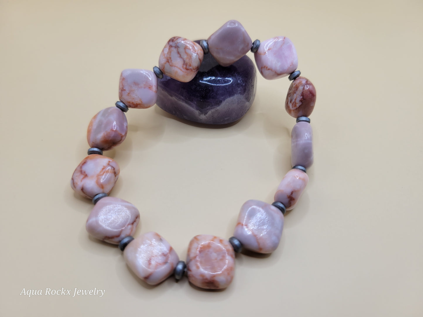 Necklace with pink and brown beads on a beige background, branded 'Aqua Rockx Jewelry'.