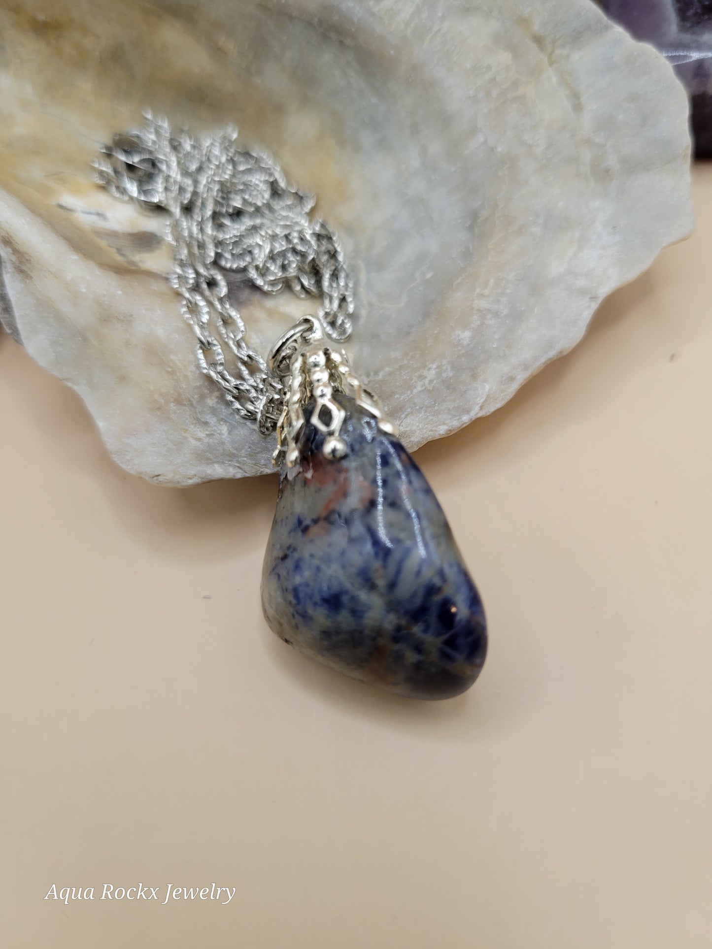 Jewelry with a blue stone and silver chain on a shell background