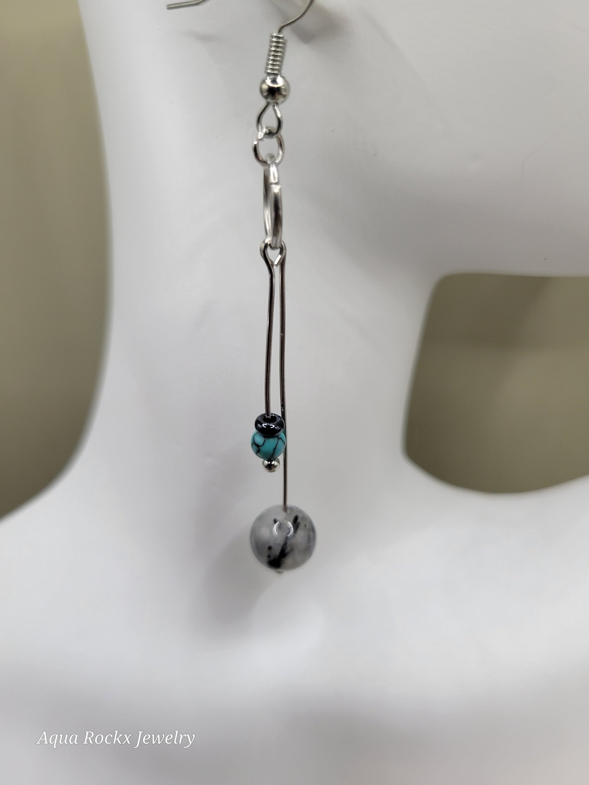 Silver earring with a turquoise gemstone on a white background