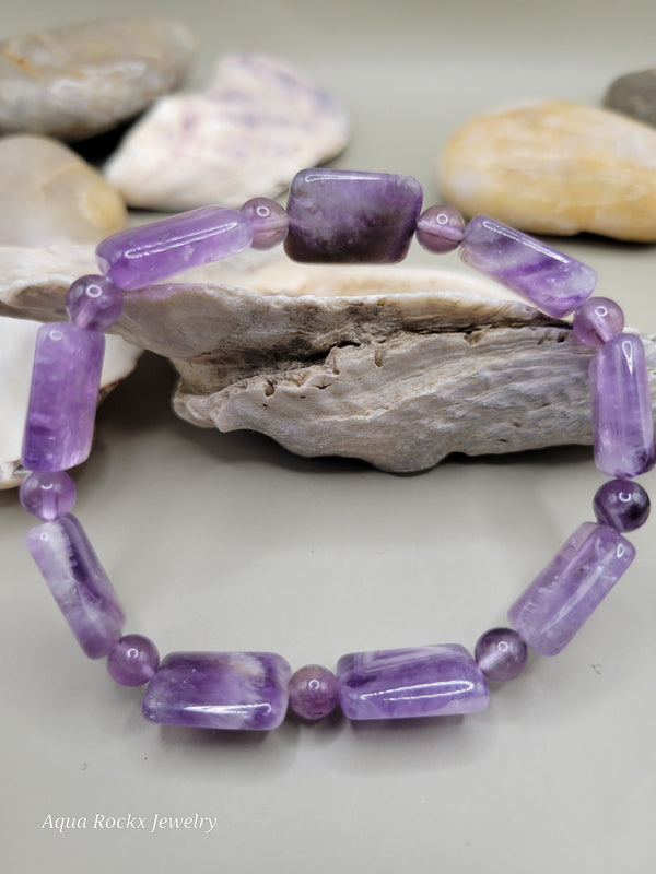 Purple beaded bracelet on a stone surface with a blurred background
