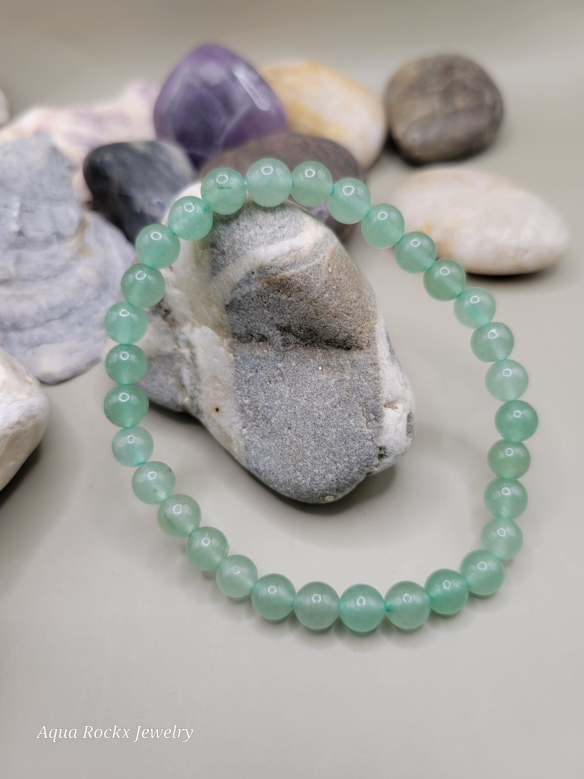Green beaded bracelet on a stack of seashells.