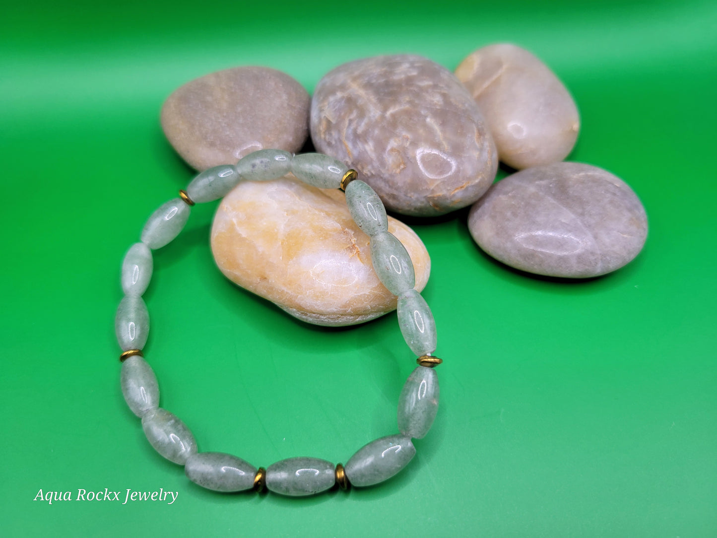 Aventurine beaded bracelet on a pile of stones with a green background