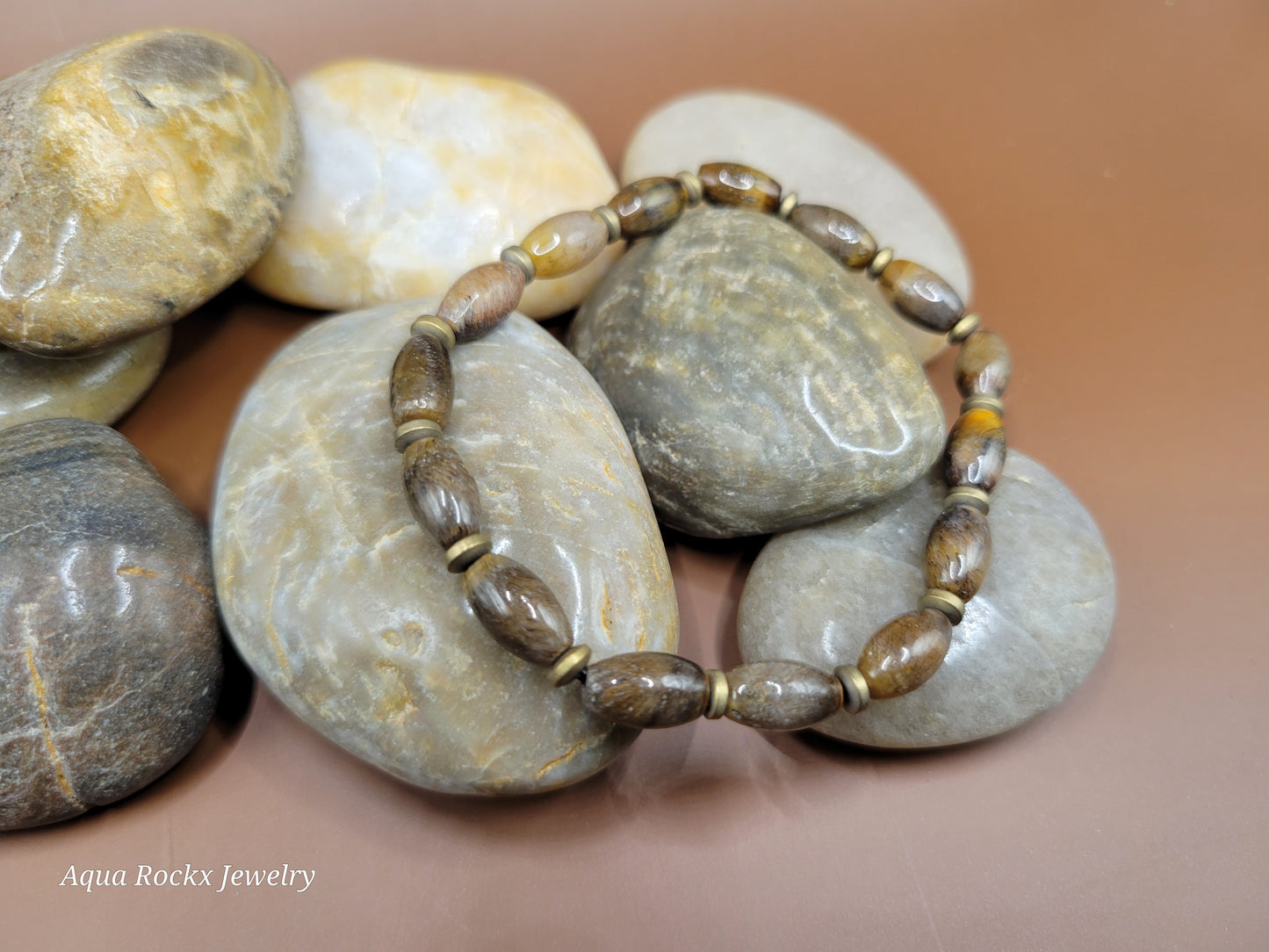 Bracelet with natural stones on a stack of stones, featuring 'Aqua Rockx Jewelry'.
