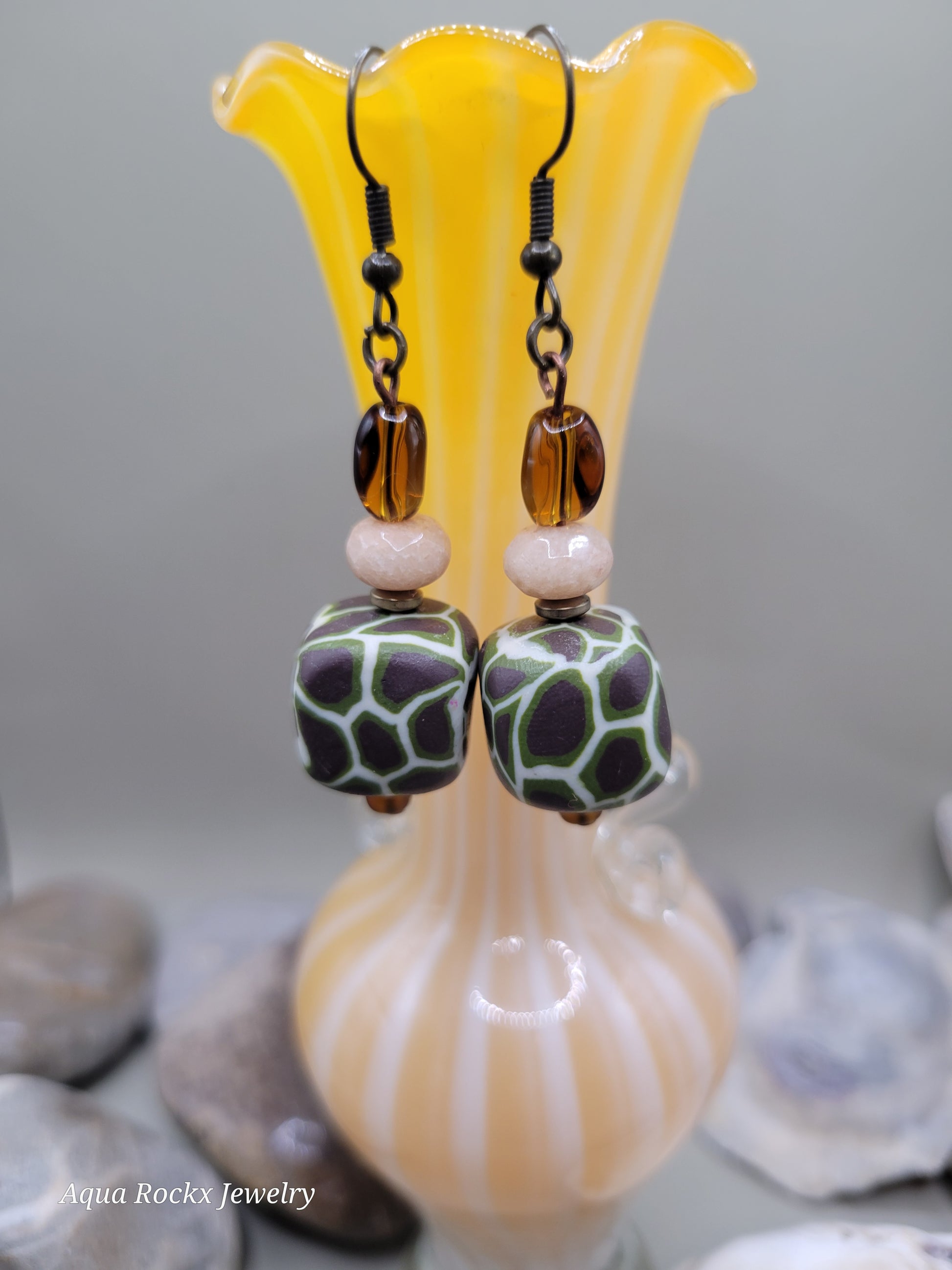 Pair of colorful beaded earrings with a shell-like object in the background