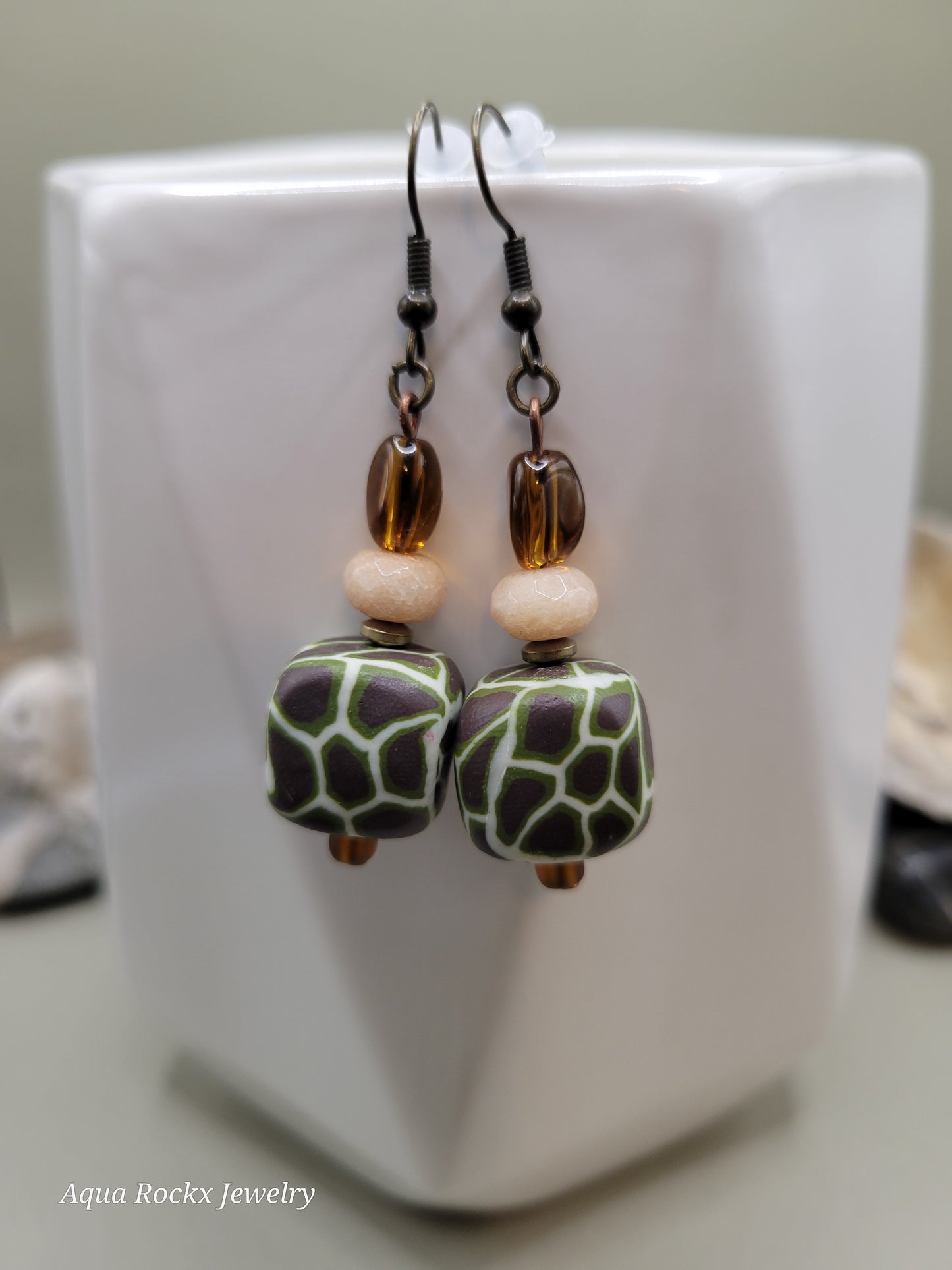Pair of earrings with green and brown beads on a white surface