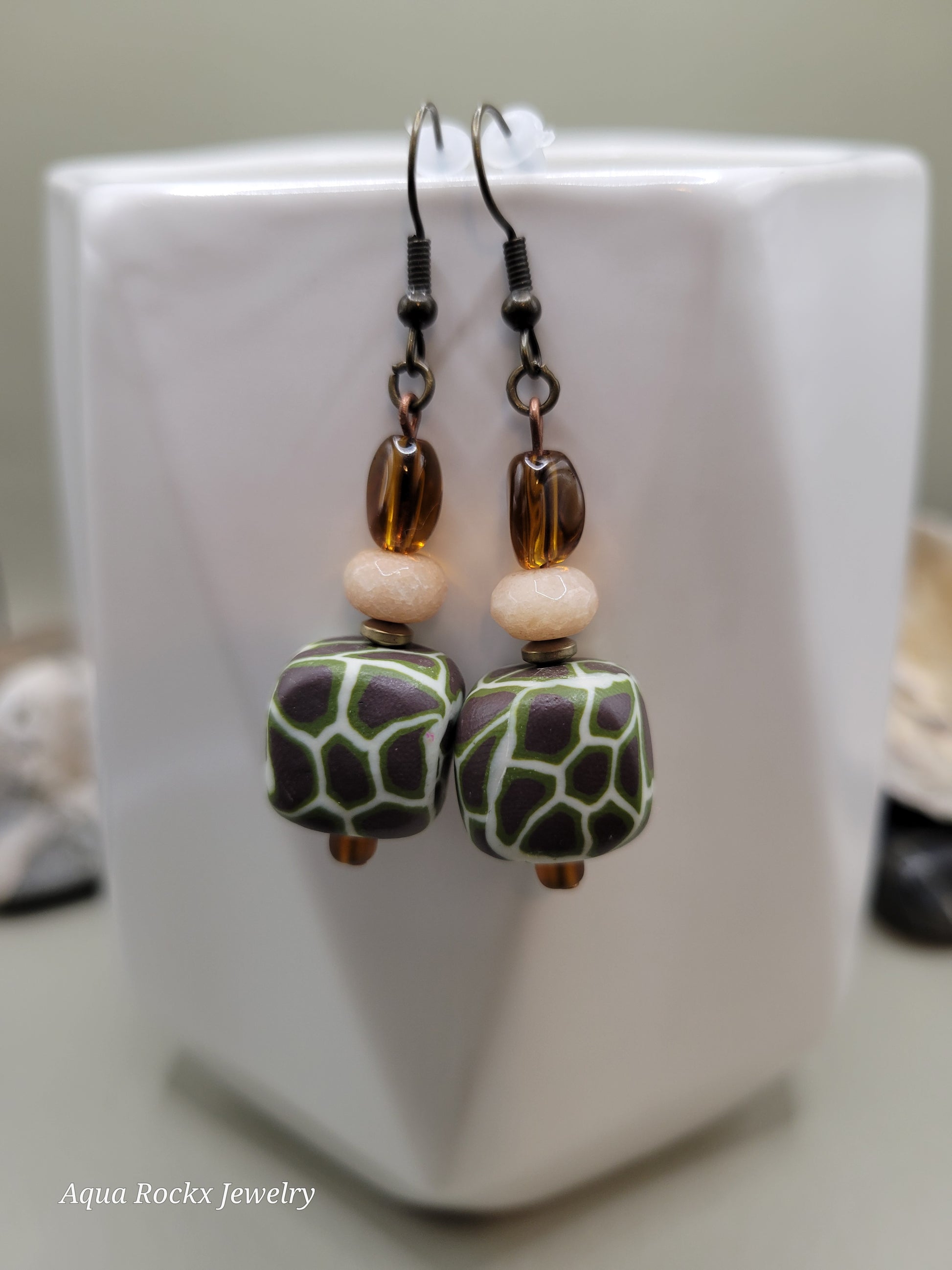 Pair of earrings with green and brown beads on a white surface