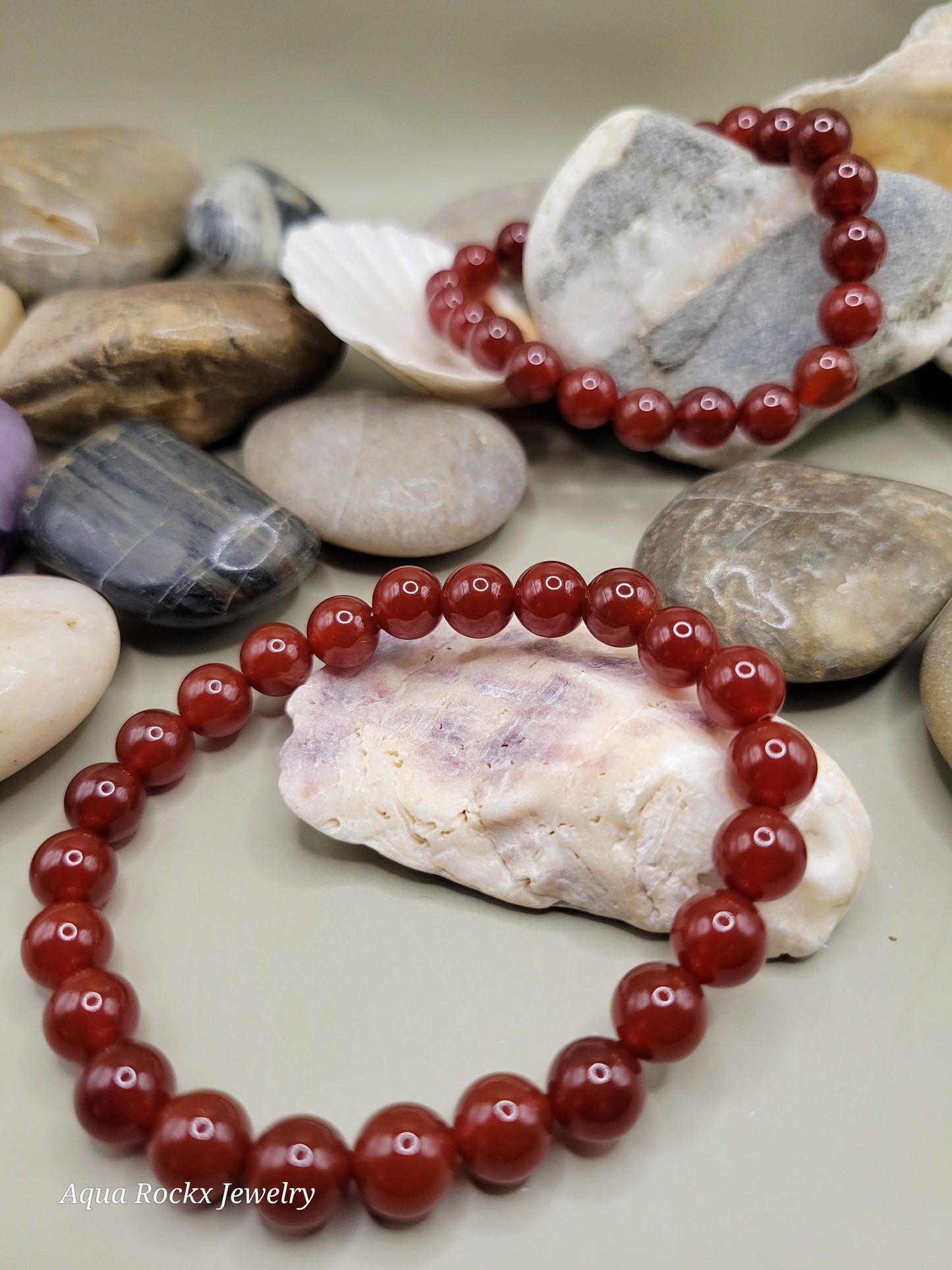 Deep orange beaded bracelet on a bed of stones 