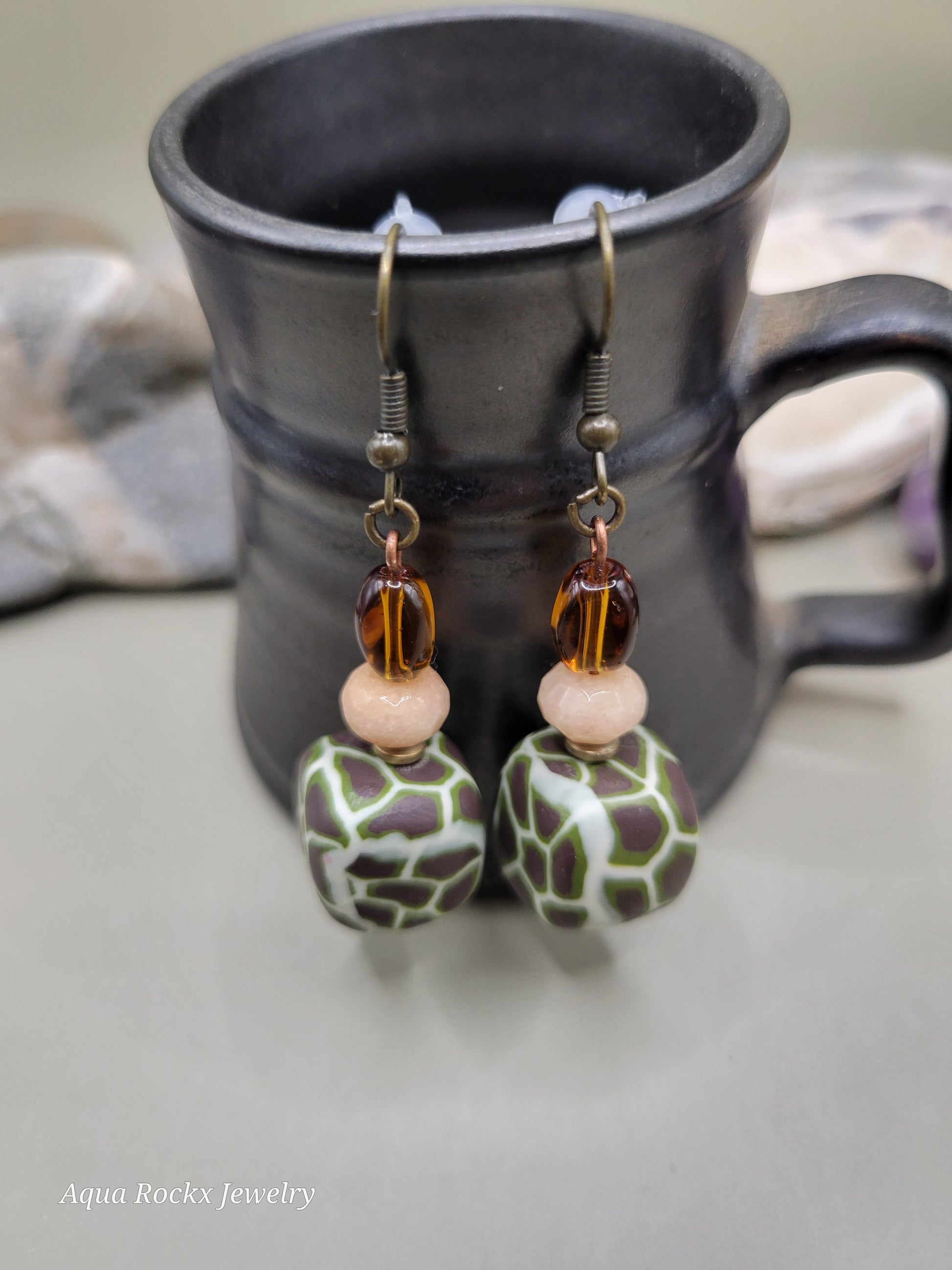 Pair of beaded earrings on a black mug with a blurred background