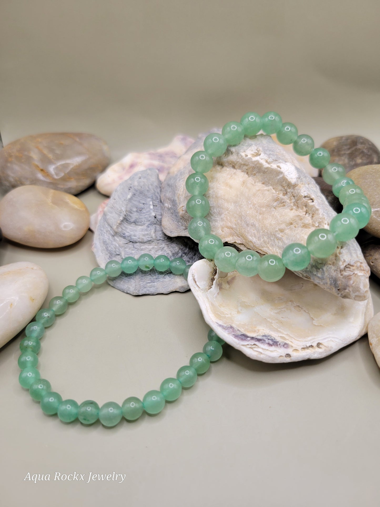 Green beaded bracelet on a shell with pebbles