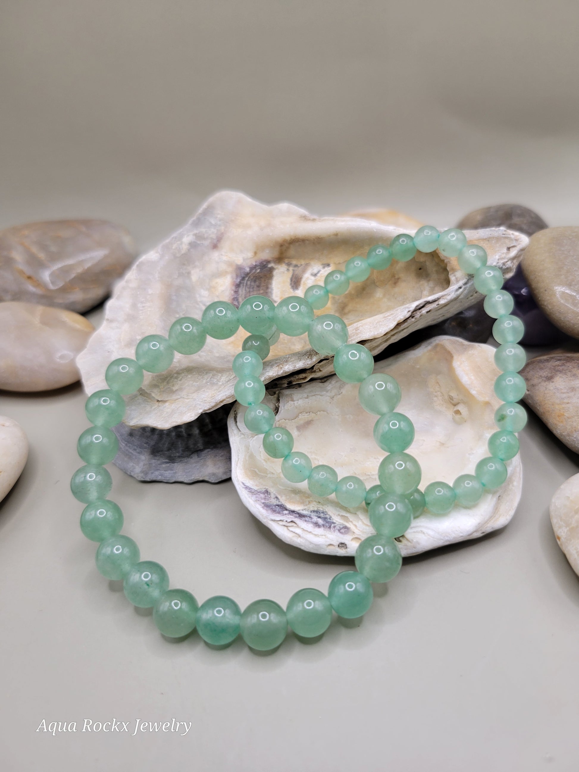 Green beaded bracelet on a shell with pebbles