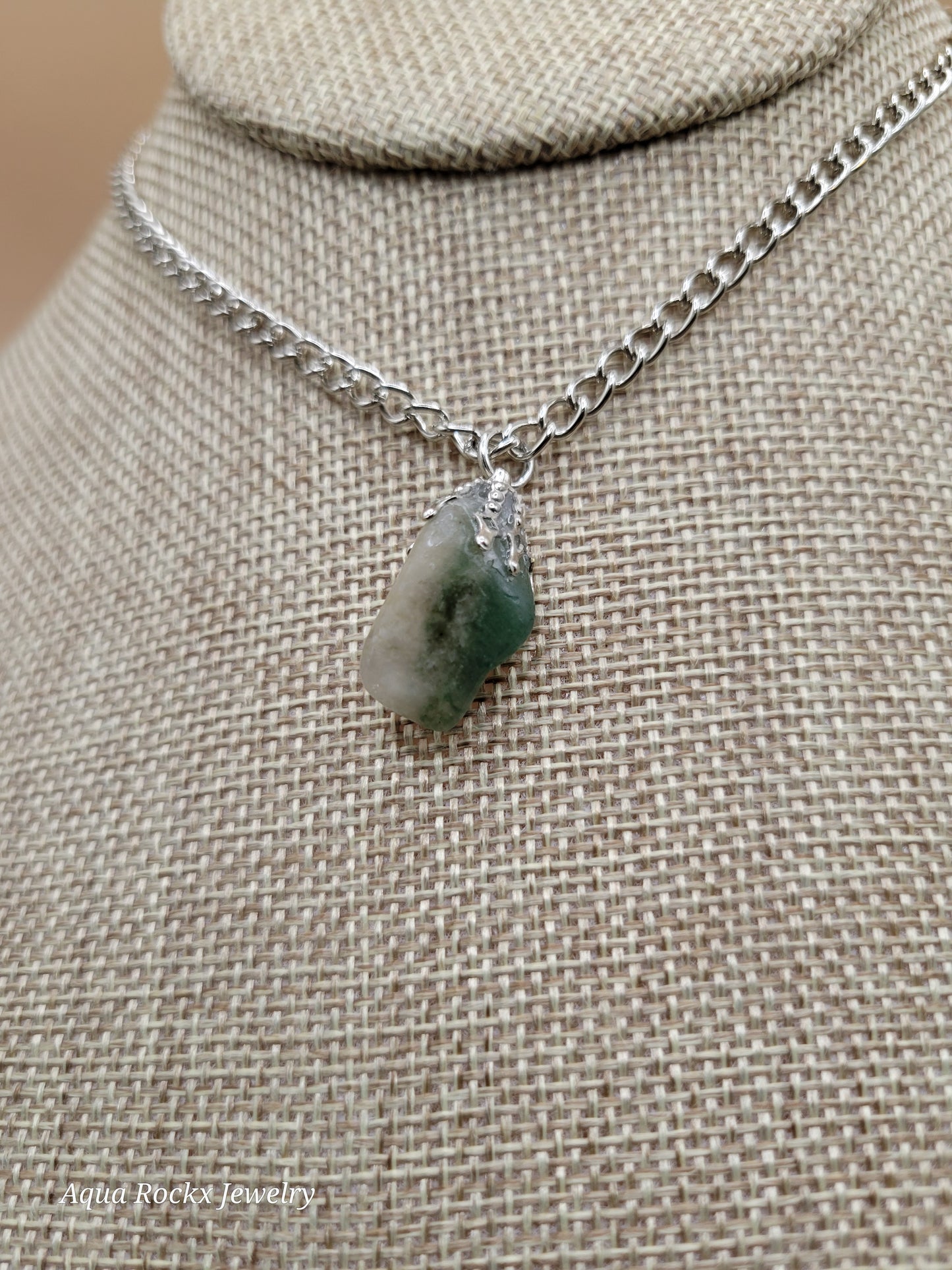 Necklace with a green stone pendant on a beige fabric background