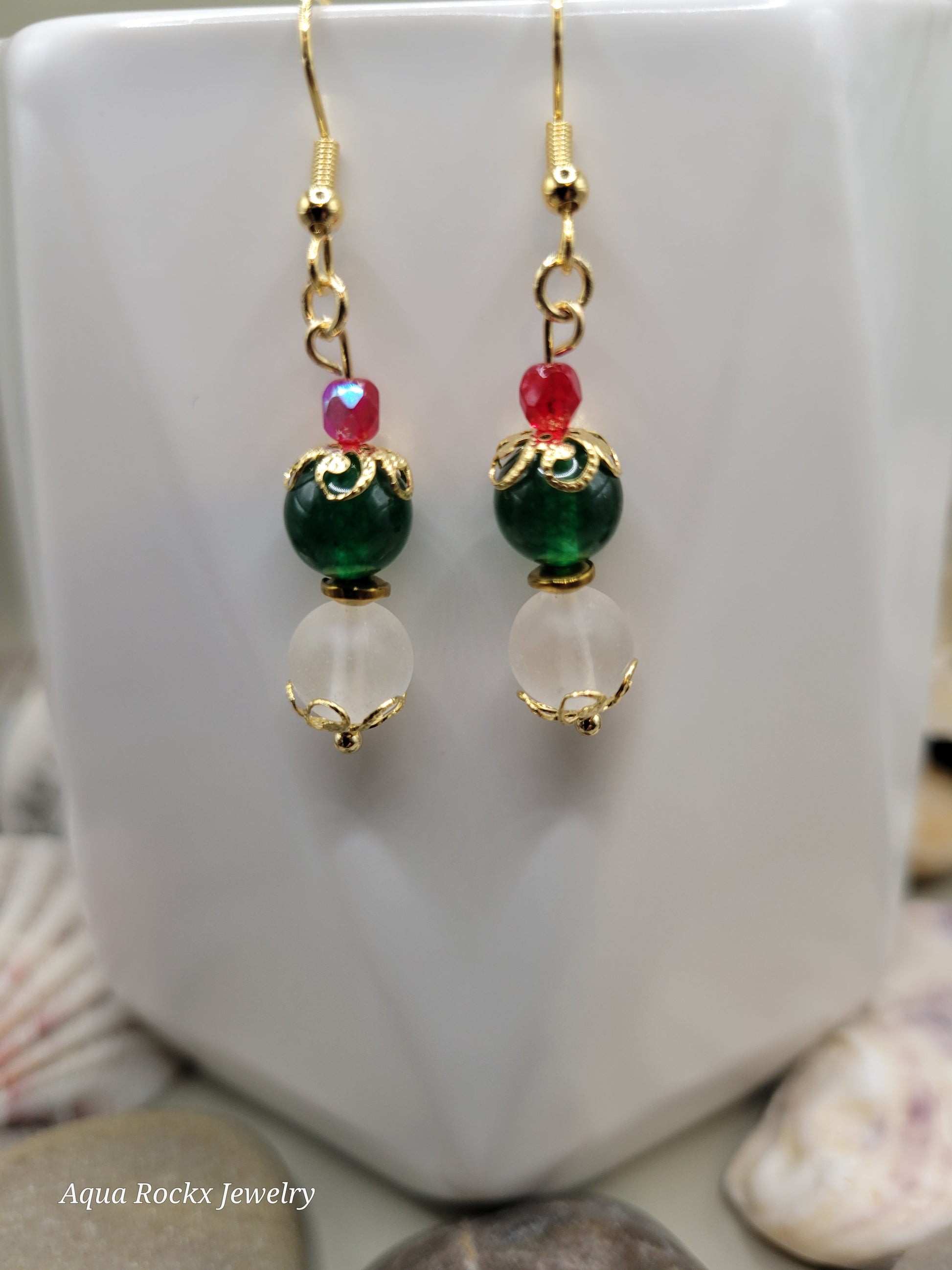 Pair of gold earrings with green, red, and clear beads on a white surface.