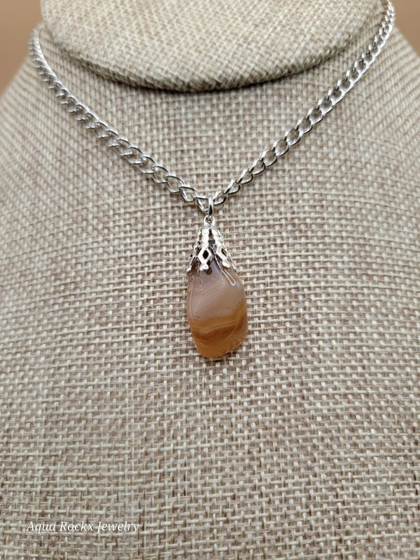 Necklace with an oragne pendant on a textured beige fabric background