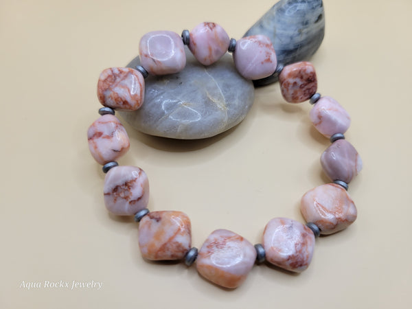 Necklace with pink and brown beads on a stone background, branded 'Aqua Rockx Jewelry'.