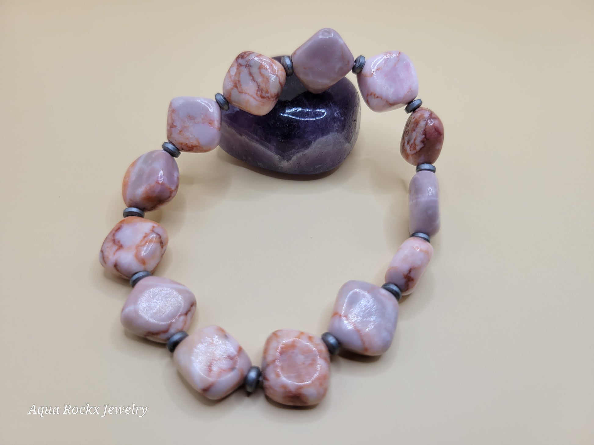 Necklace with pink and brown beads on a beige background, branded 'Aqua Rockx Jewelry'.