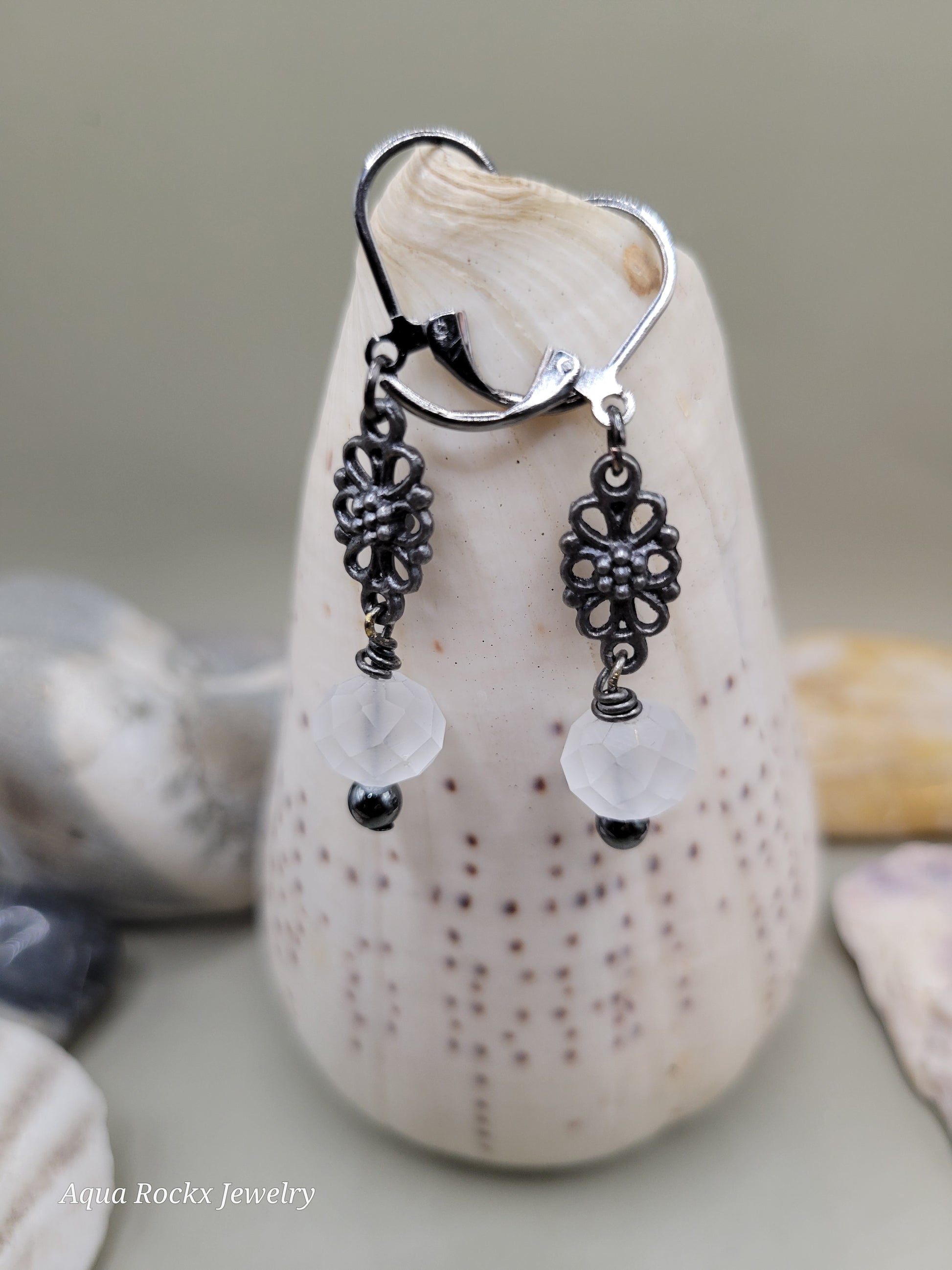 Silver and black earrings on a stone surface