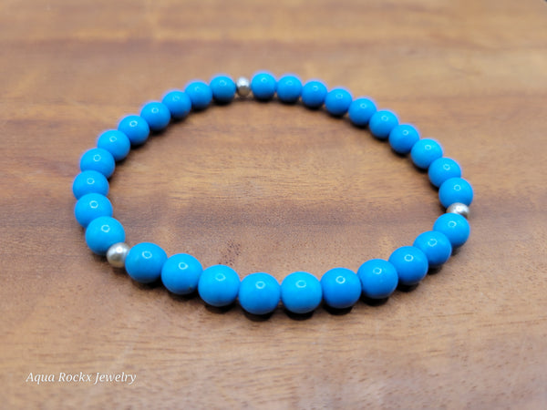 Blue beaded bracelet on a wooden surface with 'Aqua Rockx Jewelry' branding.
