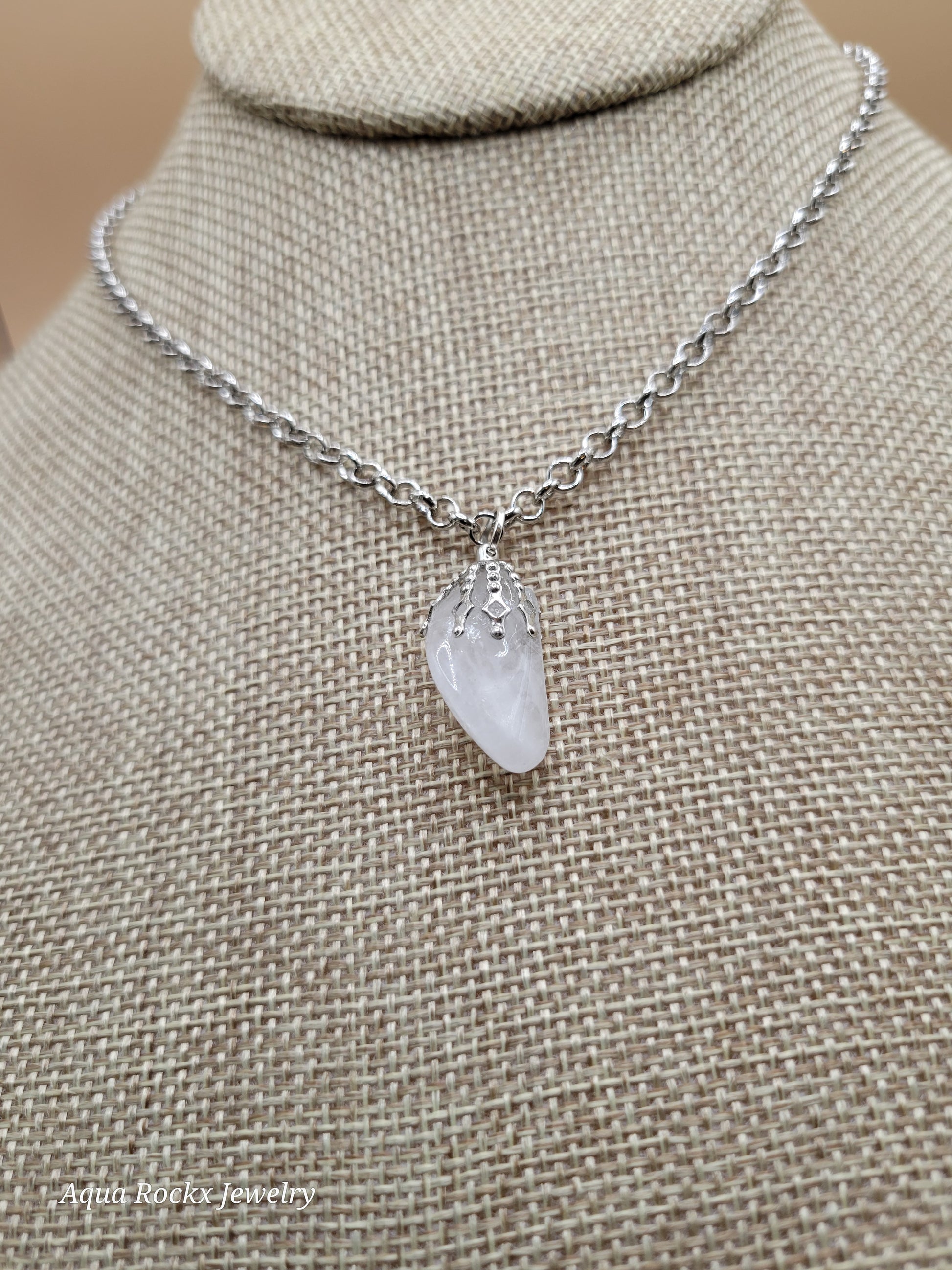 White pendant on a chain against a beige fabric background