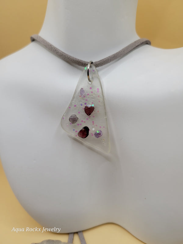 Triangle-shaped pendant with embedded stones on a mannequin bust.