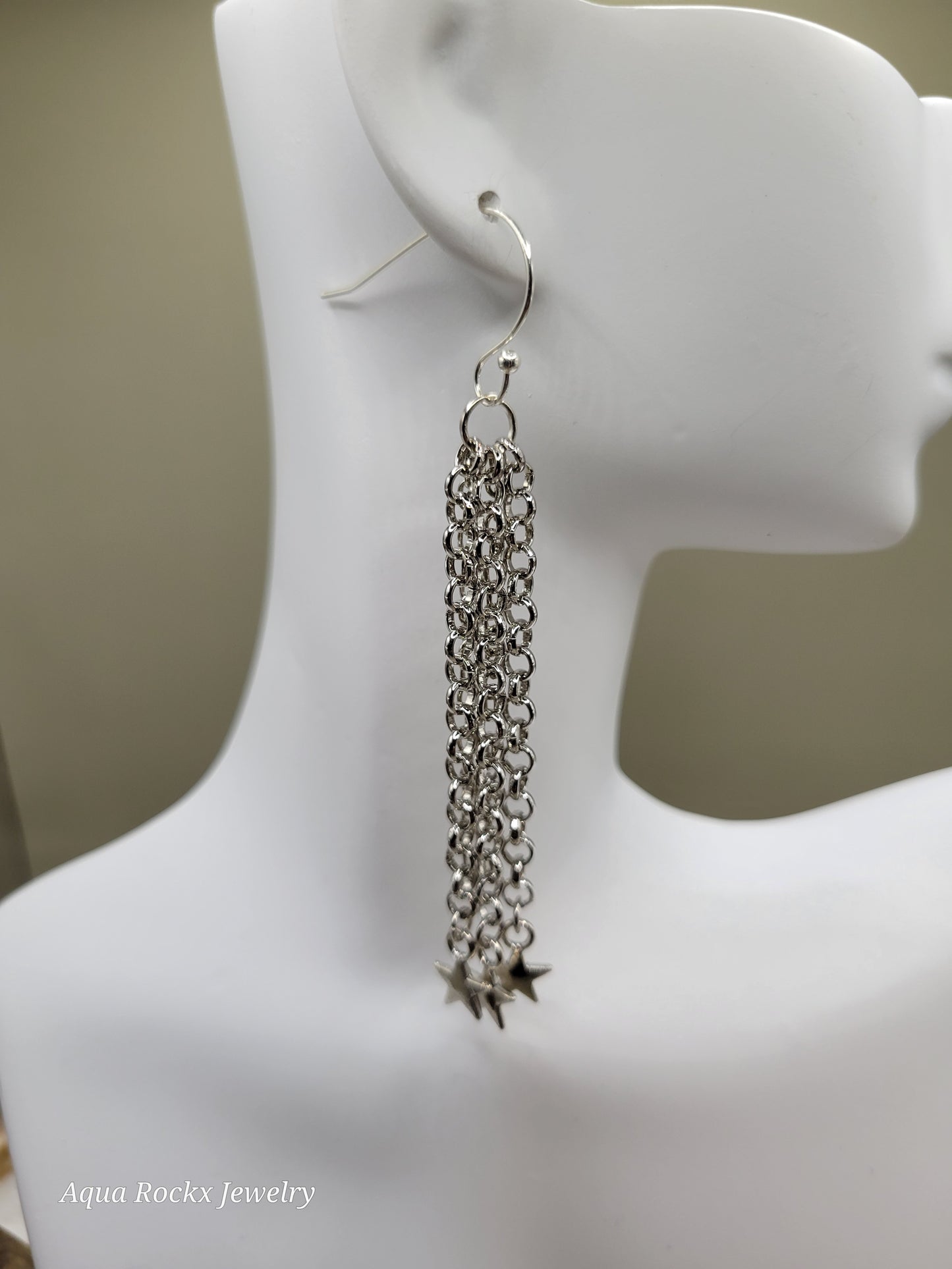 Silver chain earring on a mannequin ear with a neutral background